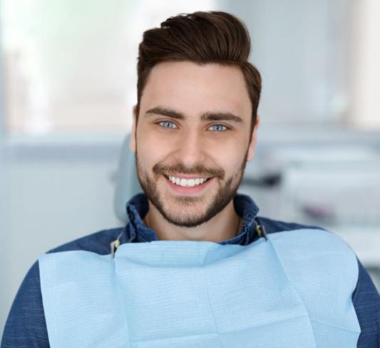 Portrait of handsome, happy male patient in dental treatment chair